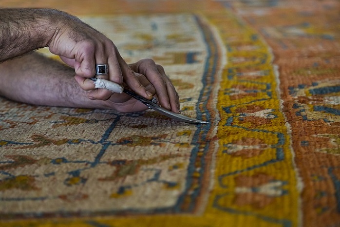 Trimming and cutting of carpet fuzz after its been produced for overseas rug retailers.